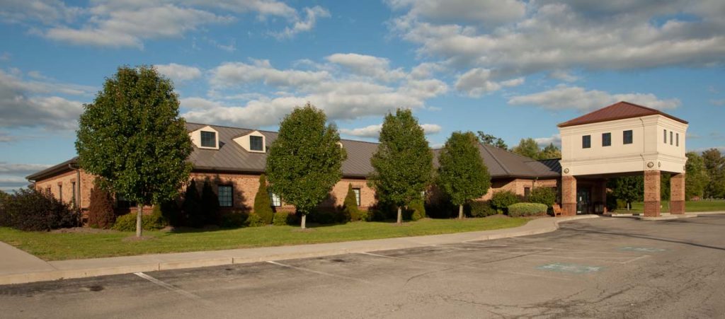 Streetview of Farrell Dental Center. A short, brick building lined with trees and shrubs