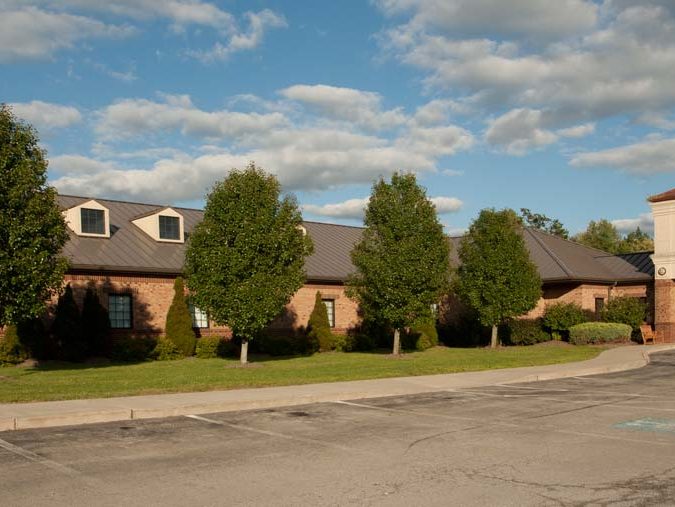 Streetview of Farrell Dental Center. A short, brick building lined with trees and shrubs