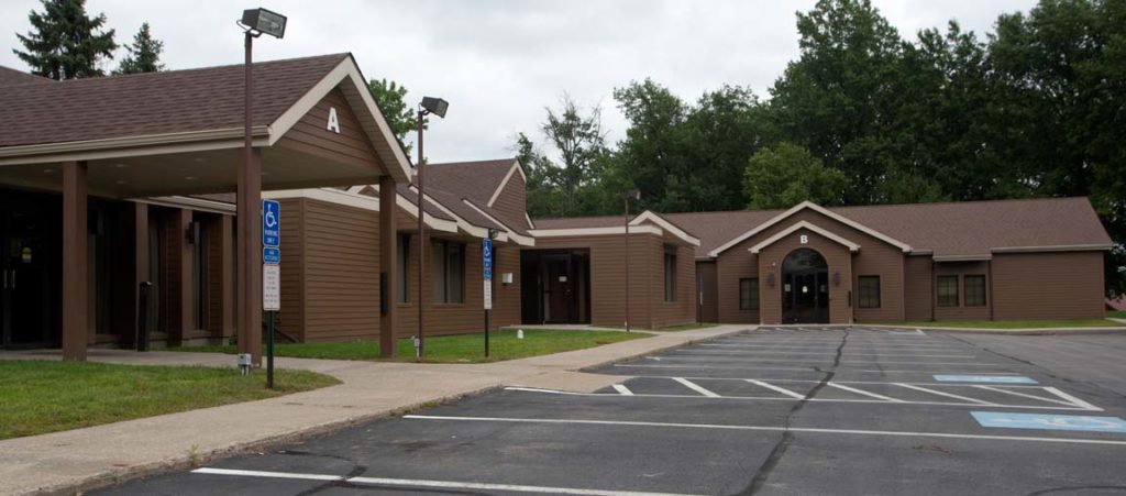 View of Green Street Primary Care from the parking lot, a dark brown building with A and B entrances