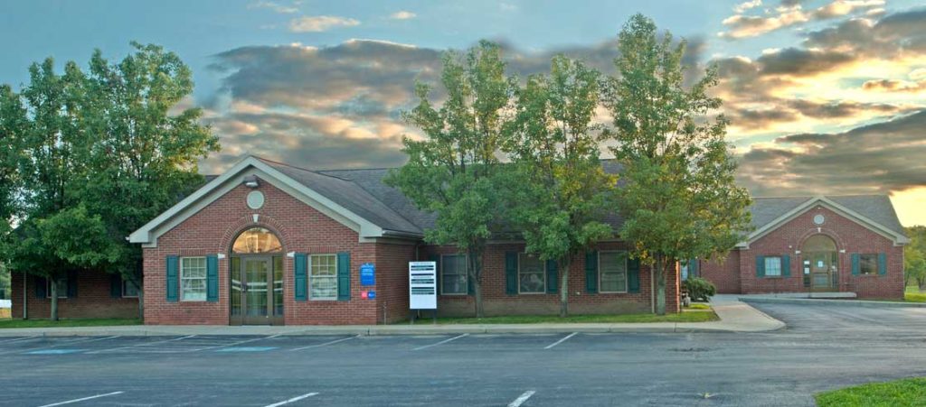 Cropped, parking lot view of side of Mercer Primary Care building entrance where sign is visible