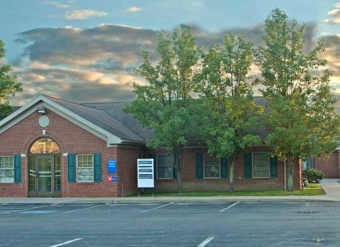 Cropped, parking lot view of side of Mercer Primary Care building entrance where sign is visible