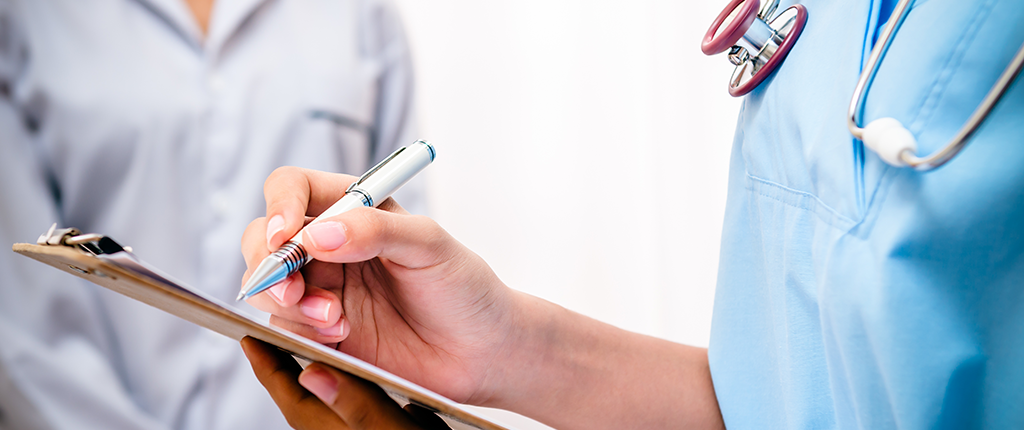 A close-up of a medical professional writing on a clipboard with a silver pen