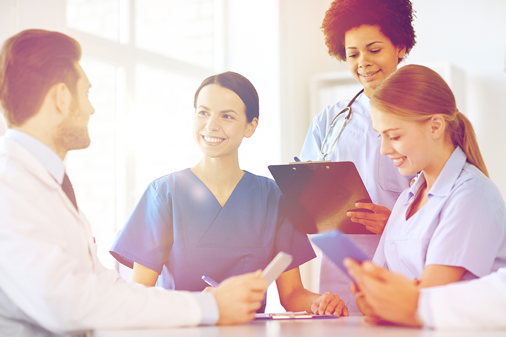 A gathering of medical professionals around a table with clipboards