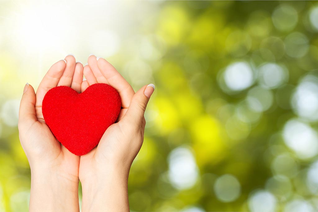 A woman's hands hold a red fabric heart, the background is distorted