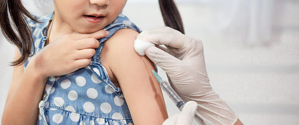 A young girl receives a vaccine in her left shoulder