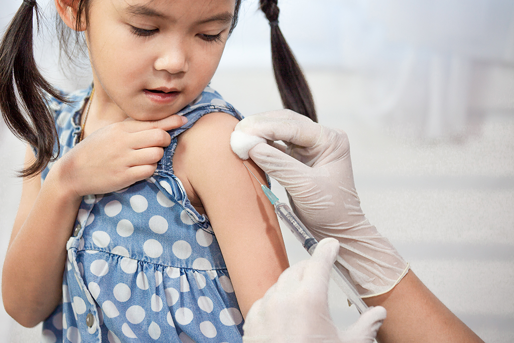 A young girl receives a vaccine in her left shoulder