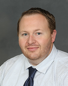 Portrait of a man wearing a white shirt with blue dots and a dark blue tie