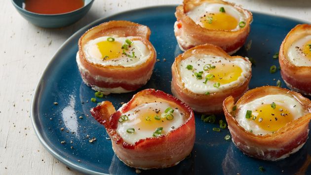 A plate full of bacon-wrapped fried eggs, topped with chives and black pepper