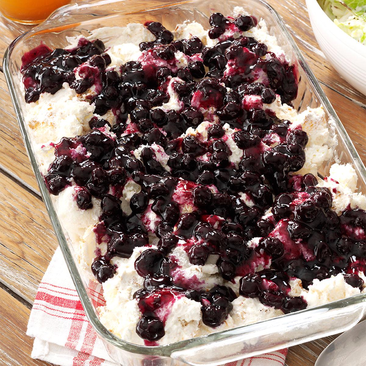 Angel food cake and cream cheese mixture in a casserole dish topped in blueberry pie filling