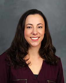 A posed woman with dark brown hair in a burgundy shirt