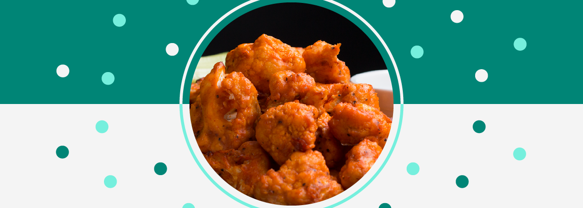 Close-up of cauliflower, breaded, in a bright red-orange buffalo sauce, green and white background