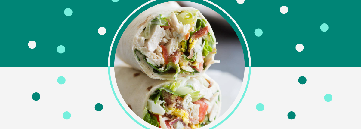 Close-up, two halves of a wrap filled with lettuce, chicken, bacon, tomato, and hardboiled egg