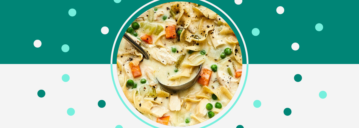 Creamy chicken noodle soup with peas, carrot, and celery on a green and white background