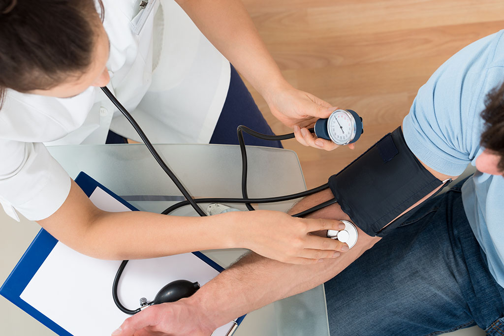 A medical professional uses a stethoscope to check a man's blood pressure