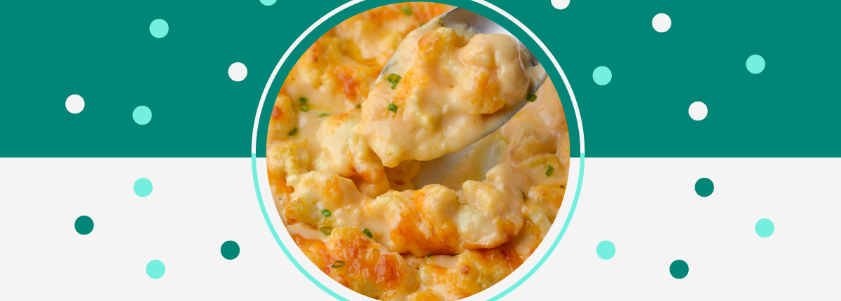 Close-up top-view of cheesy baked cauliflower casserole topped with chives and a spoon holding scoop
