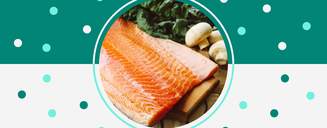 Close-up of raw salmon on a cedar plank with spinach and mushrooms in the background