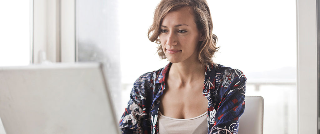 A woman sitting down uses a laptop