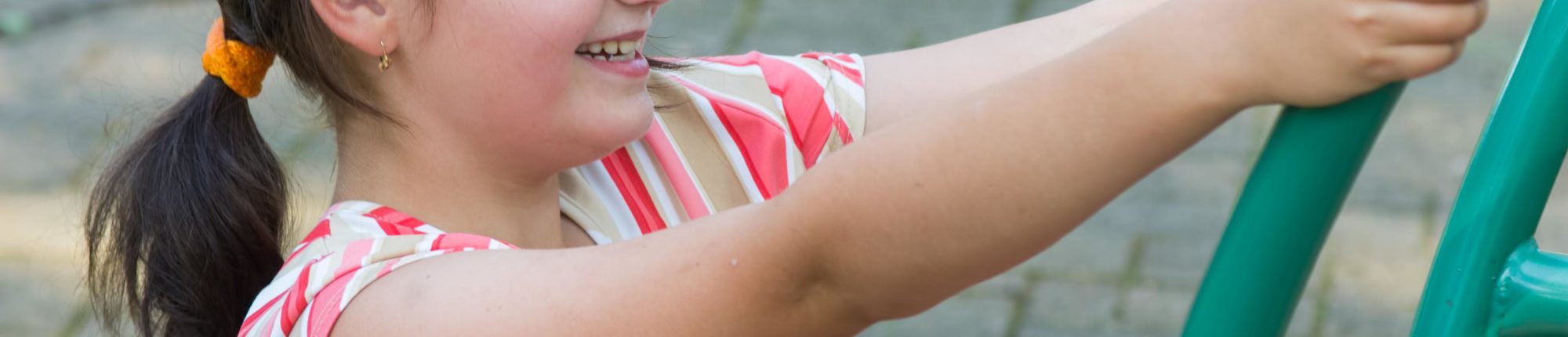 Extreme close up of a young girl smiling while she plays on metal playground equipment