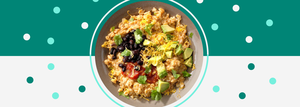 Tex mex grain bowl full of cooked oats topped with black beans, avocado, salsa, cheese, and cilantro