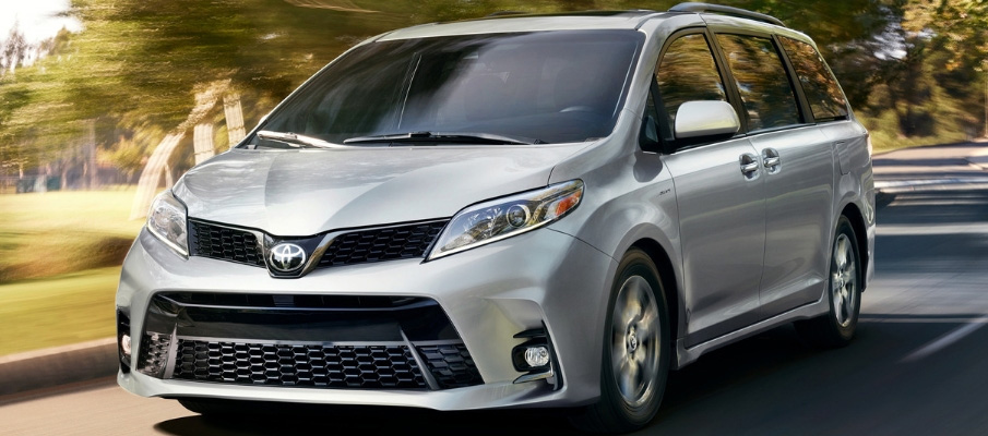 Action road view of silver 2018 Toyota Sienna van on road with blurred green landscape