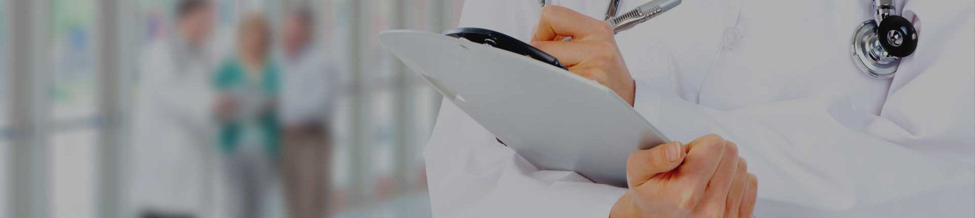 Medical doctor holding clipboard in right hand while writing notes with left hand