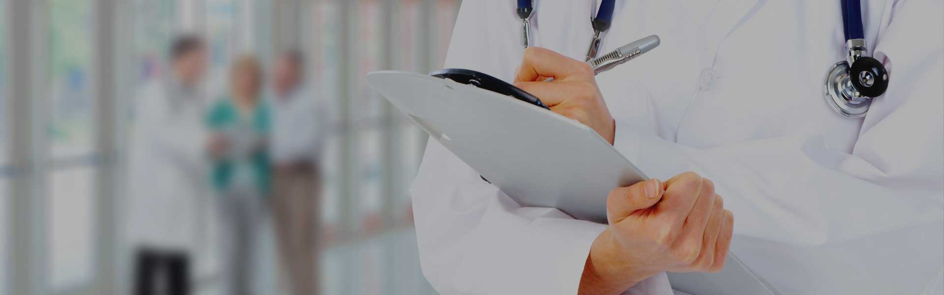 Medical doctor holding clipboard in right hand while writing notes with left hand