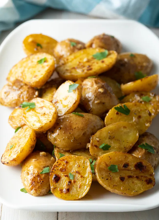 Roasted Greek lemon potatoes, fork poking baby potatoes with Greek lemon sauce 