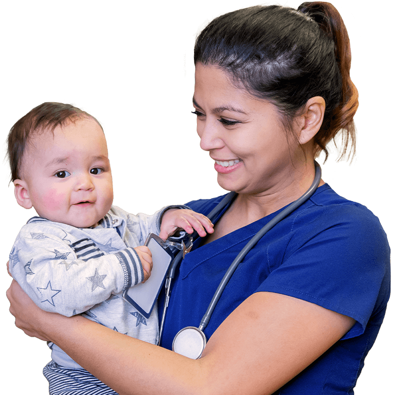 A nurse wearing blue scrubs holds a smiling infant