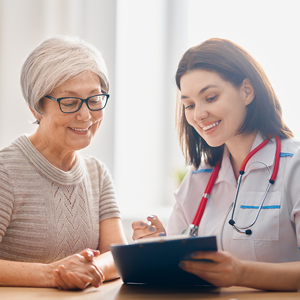 Medical professional reviewing notes on a clipboard with a patient 