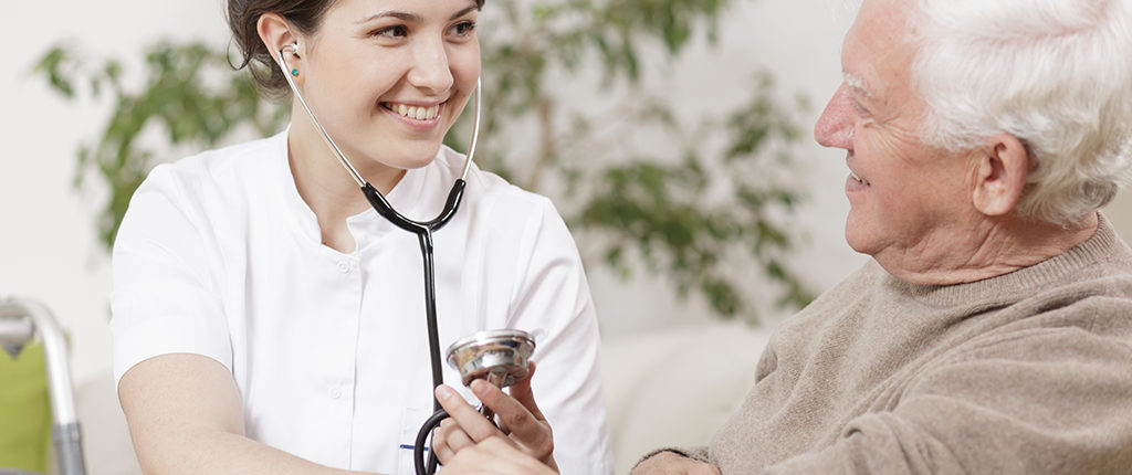 A woman wearing a stethoscope is looking at an older man