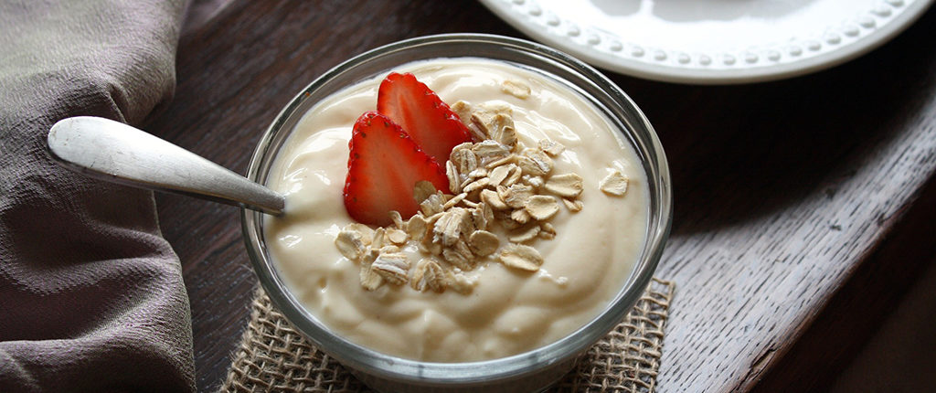 Close-up of yogurt with almond slivers and strawberry pieces. Food is in color, table is grayscale