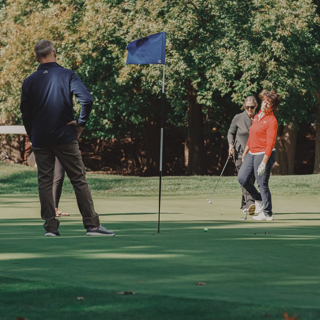 A group of golfers near a hole flag