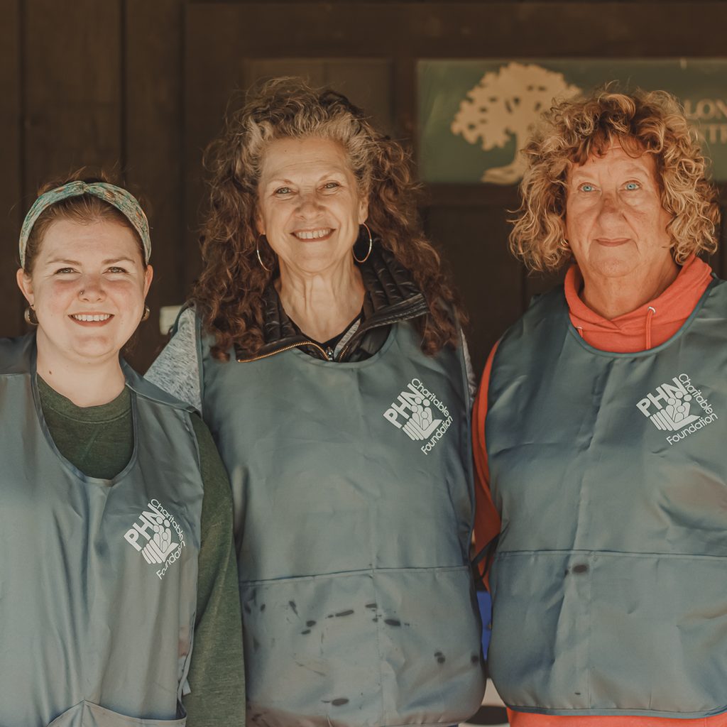 Three female golf volunteers smiling at the camera