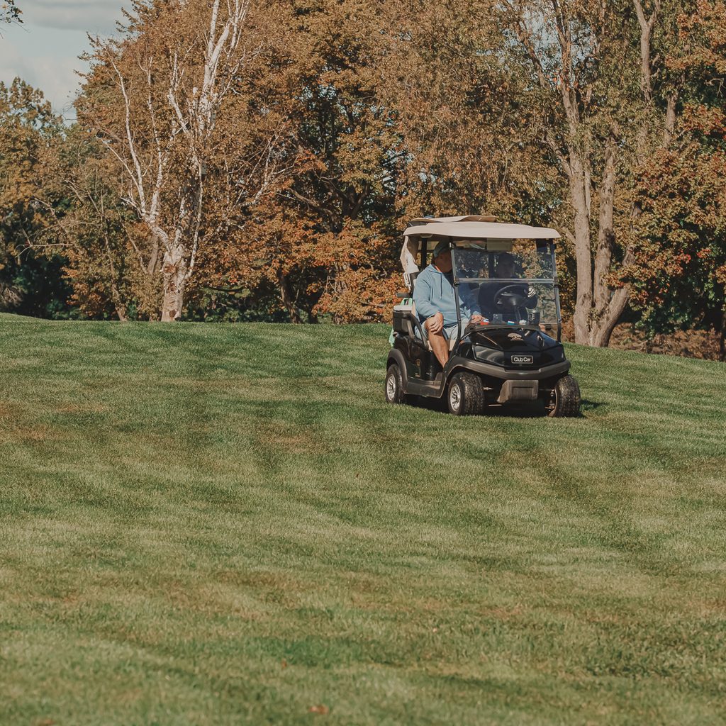 A golf cart driving down the fairway