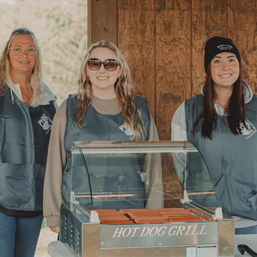 Female golf volunteers standing behind a hot dog grille
