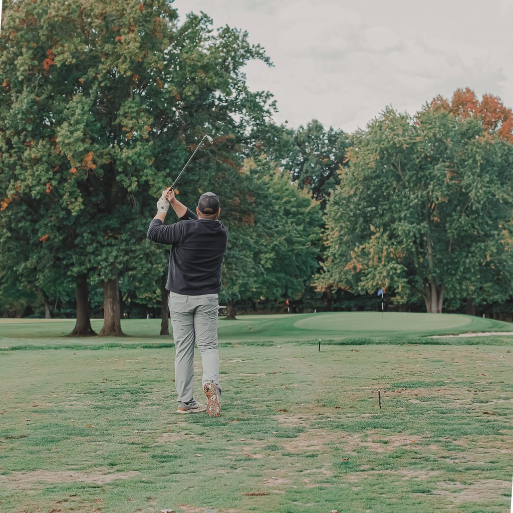 A male golfer hitting from the rough