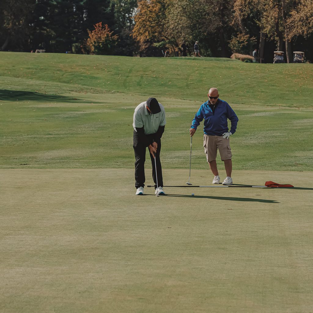 two golfers standing on a putting green