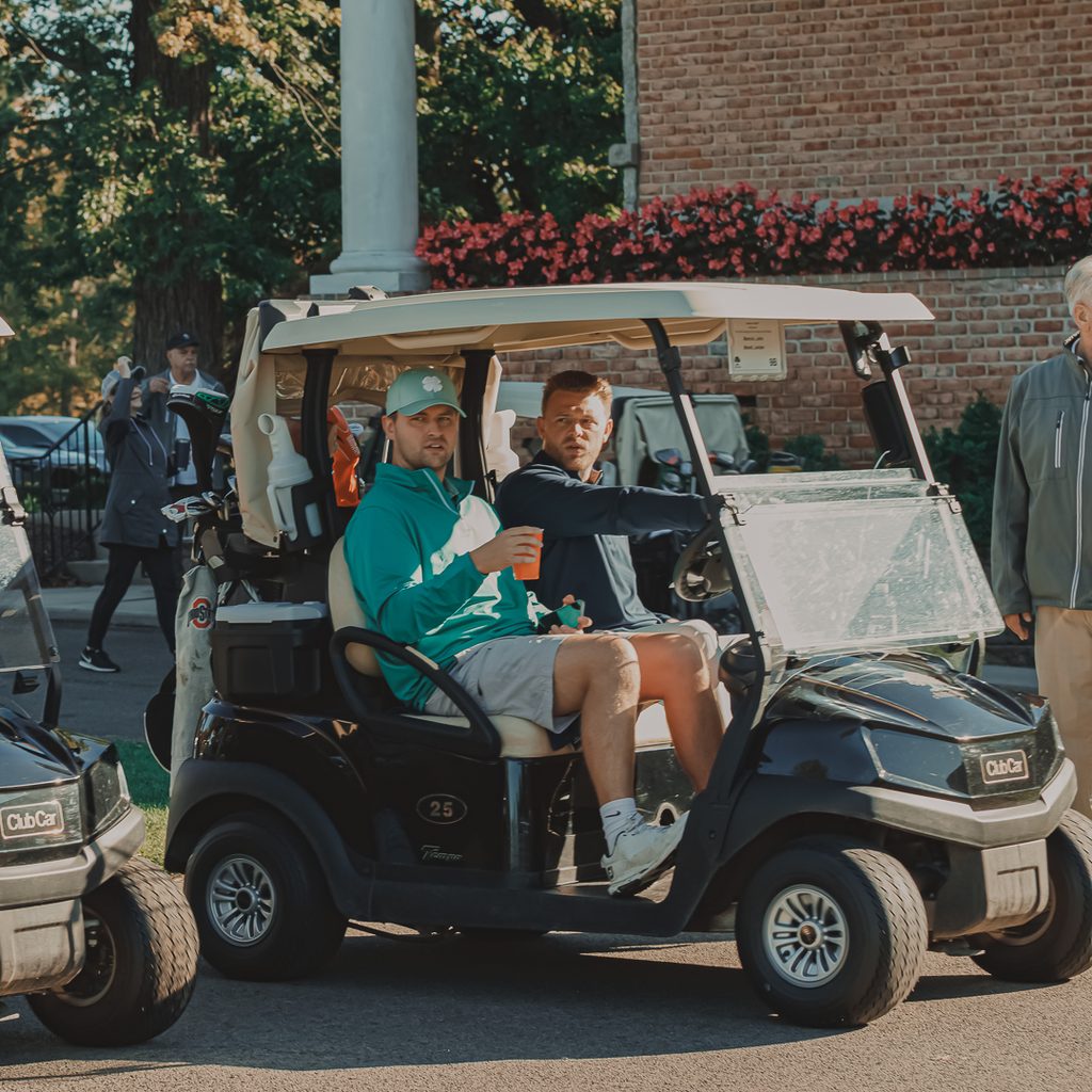 Two golfers driving past in a golf cart