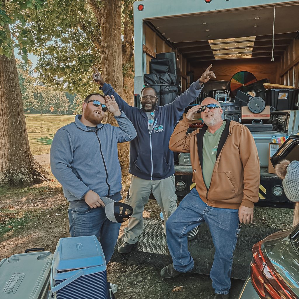 3 male volunteers standing in front of a truck