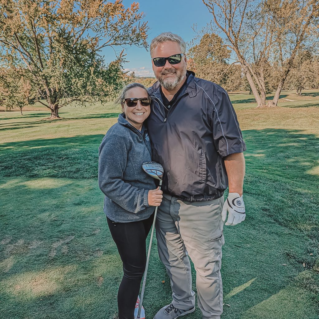 A couple posing for a photo with a golf club